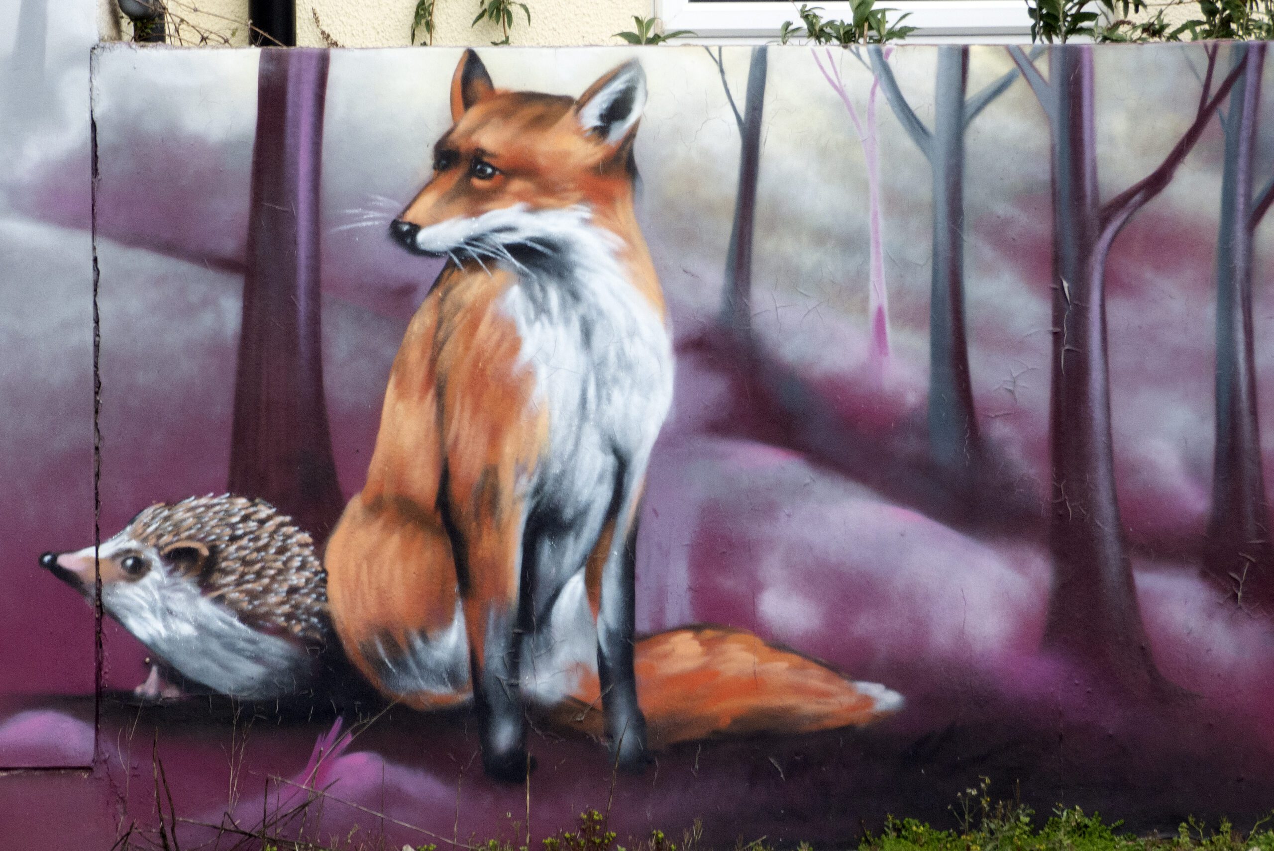 Graffiti artwork of a fox and a hedgehog. The fox is sitting down with the hedgehog behind it.